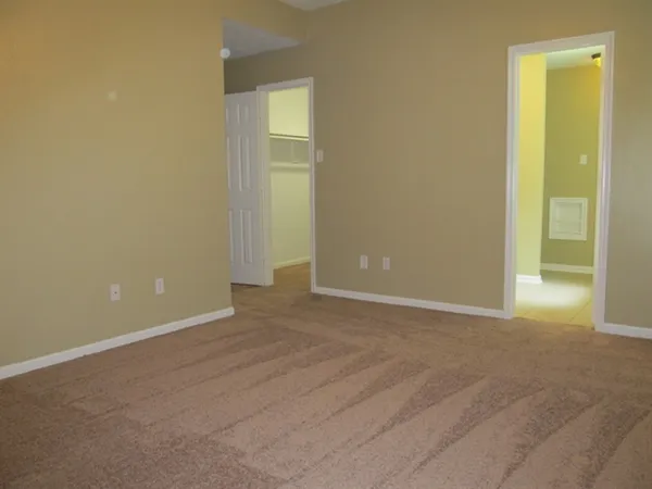 a view of an empty room with closet and a bathroom