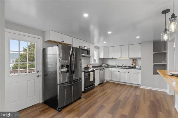 a kitchen with a refrigerator stainless steel appliances wooden floor and window