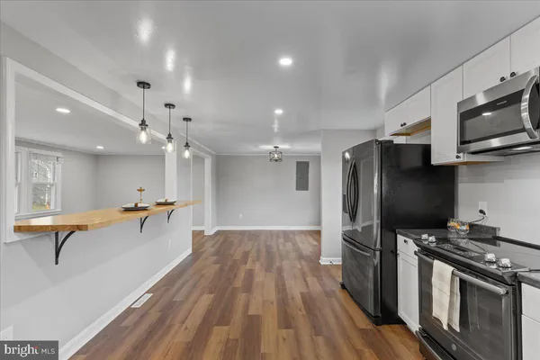 a kitchen with stainless steel appliances a refrigerator a stove top oven a sink dishwasher and a dining table with wooden floor