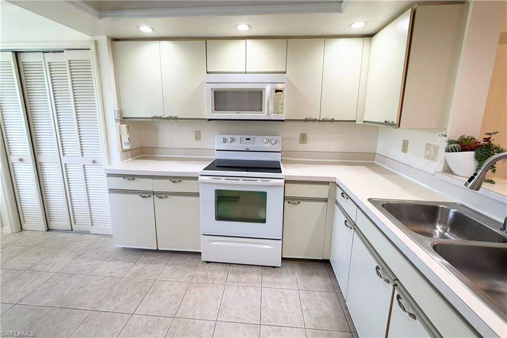 7360 St Ives Way, Unit 2205 Naples, FL 34104 - Photo 12 of 37 a kitchen with a stove sink and cabinets