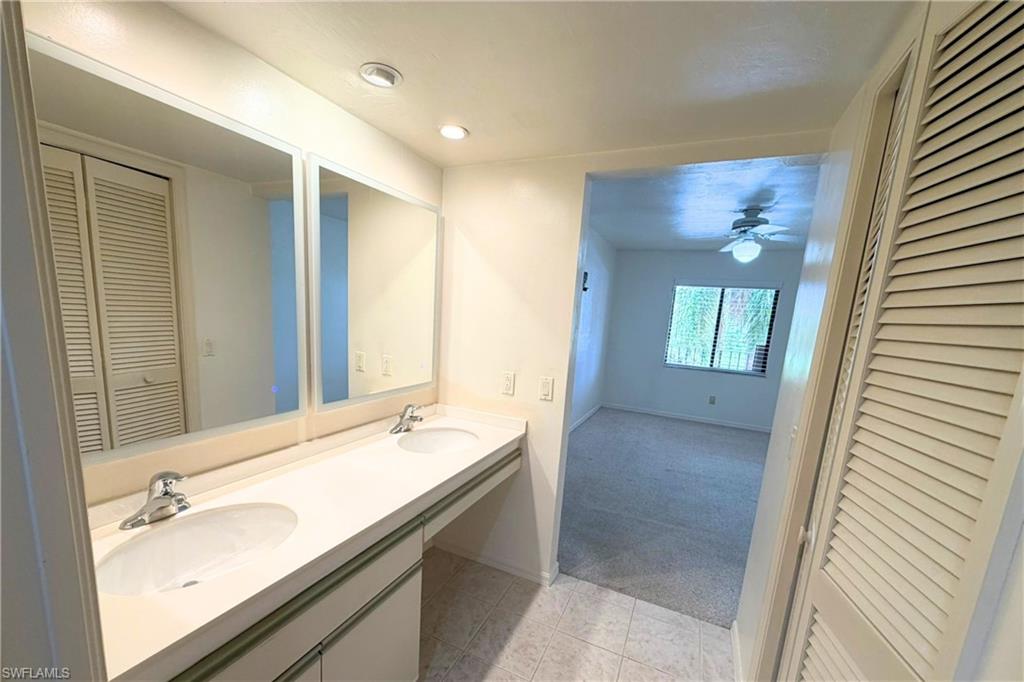 7360 St Ives Way, Unit 2205 Naples, FL 34104 - Photo 24 of 37 a bathroom with a granite countertop sink and a mirror