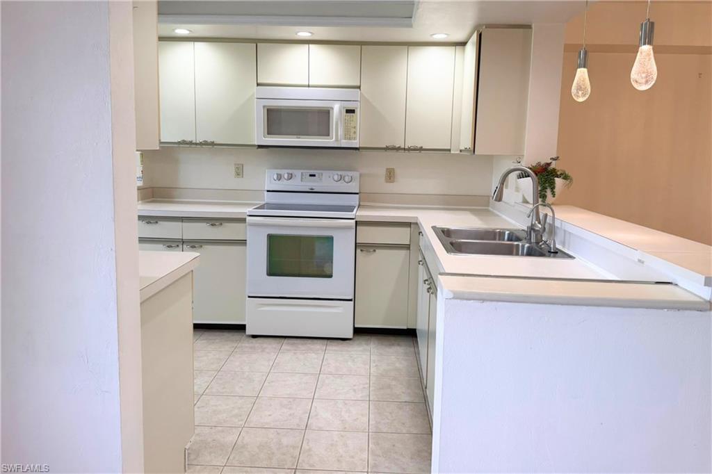7360 St Ives Way, Unit 2205 Naples, FL 34104 - Photo 10 of 37 a kitchen with a stove a sink and a microwave