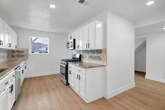 a kitchen with granite countertop white cabinets and white appliances