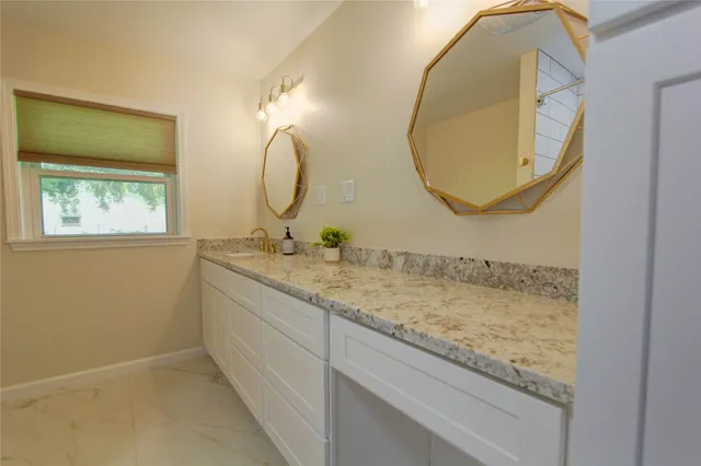a bathroom with a granite countertop sink and a mirror