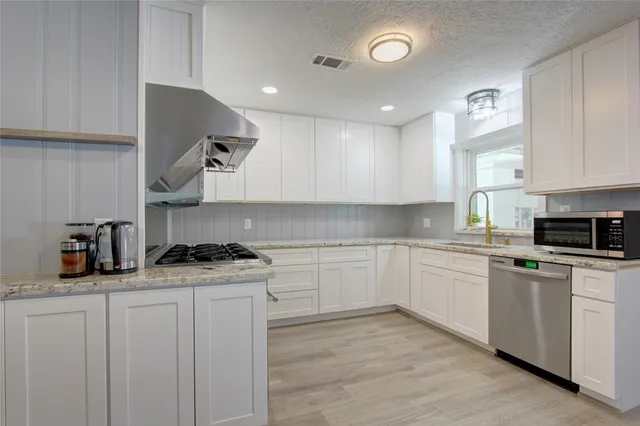a kitchen with stainless steel appliances granite countertop a stove sink and cabinets
