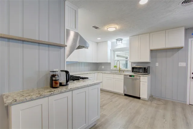 a kitchen with granite countertop white cabinets and white appliances