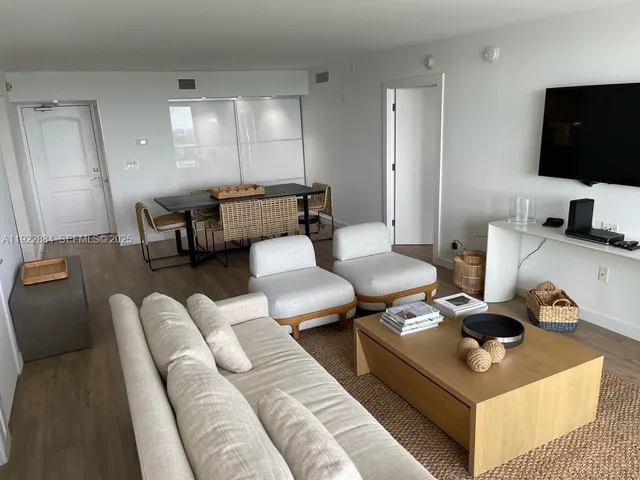 a living room with furniture a flat screen tv and kitchen view