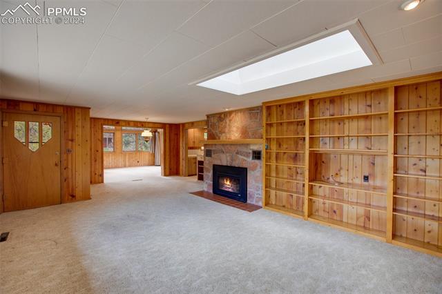 4980 Dodd Road Cascade, CO 80809 - Photo 23 of 48 Unfurnished living room featuring a fireplace, wood walls, and carpet flooring