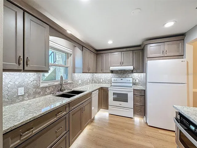 a kitchen with granite countertop a sink stove and refrigerator