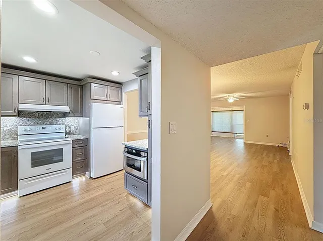 a view of a kitchen with a stove wooden cabinets and wooden floor