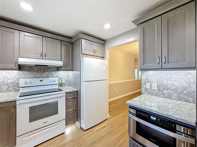 a kitchen with granite countertop a refrigerator stove and cabinets