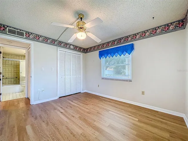 a view of a big room with wooden floor closet and chandelier fan