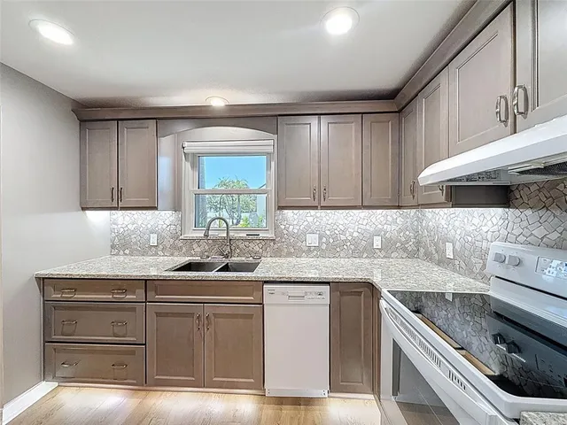 a kitchen with stainless steel appliances granite countertop a sink stove and cabinets