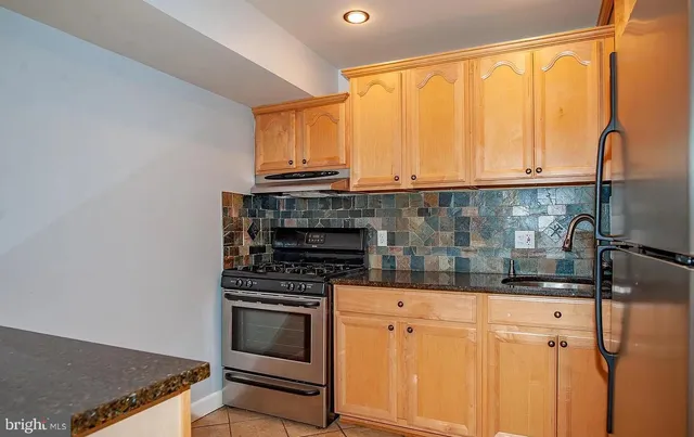 a kitchen with granite countertop a sink cabinets and stainless steel appliances