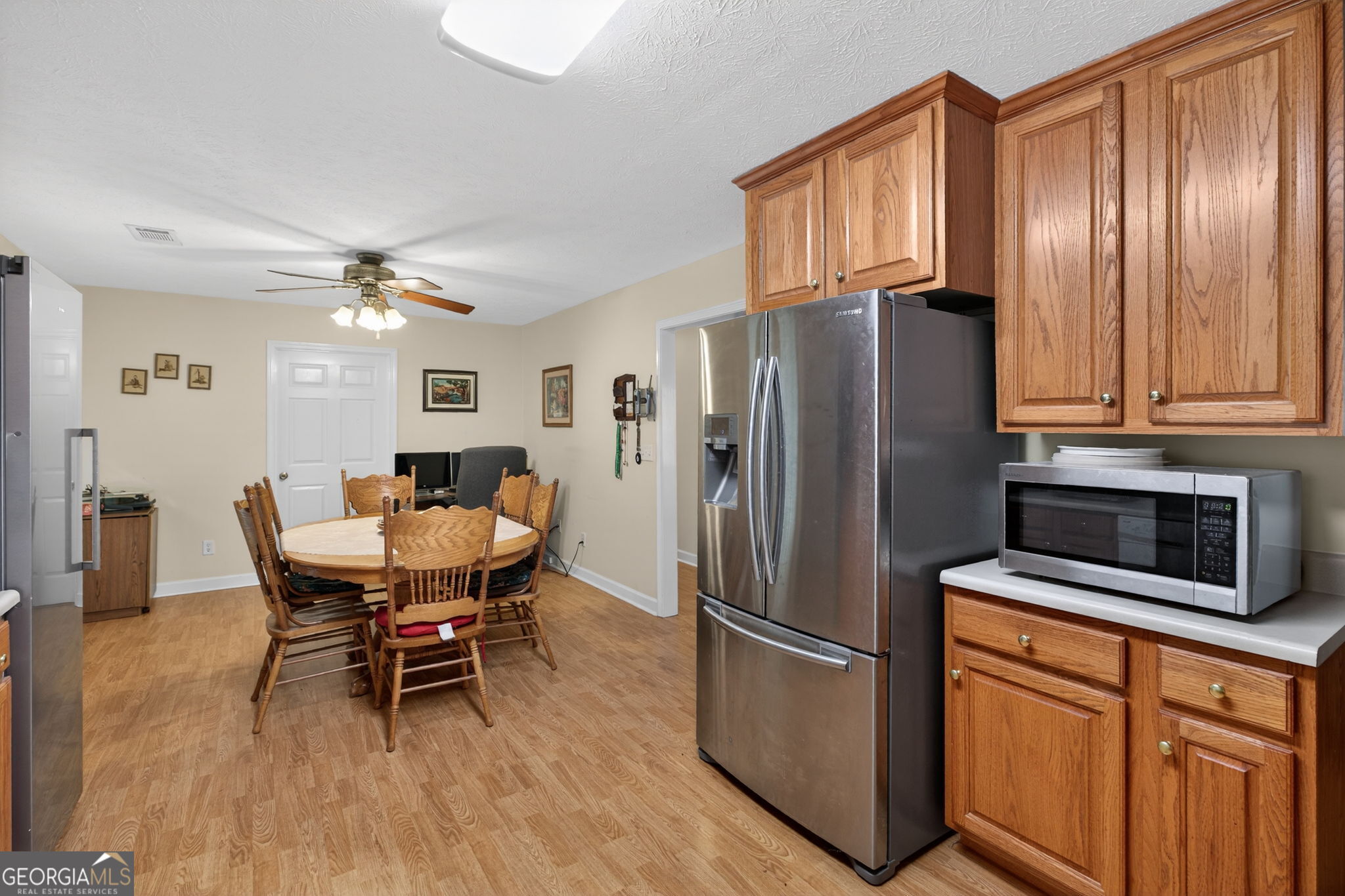 5010 Highway 27 Franklin, GA 30217 - Photo 10 of 39 a kitchen with stainless steel appliances a refrigerator a stove a dining table and chairs with wooden floor