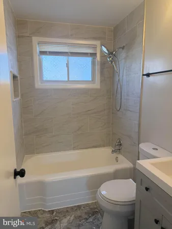 a bathroom with a granite countertop bathtub shower sink vanity and toilet