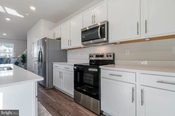 a kitchen with stainless steel appliances granite countertop white cabinets a sink a stove a refrigerator and a microwave