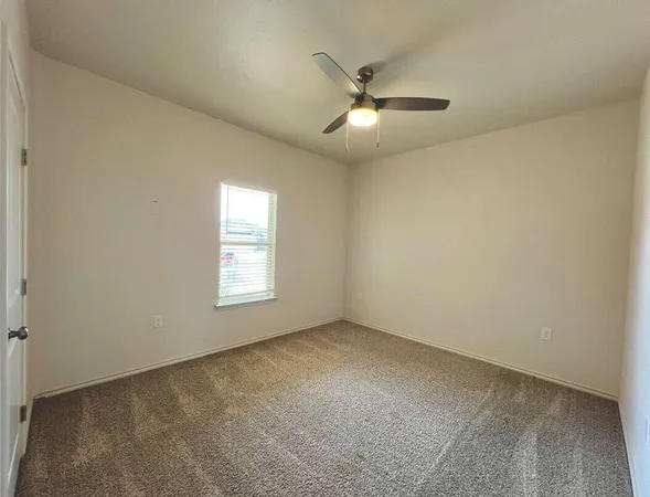 an empty room with a window and a fan