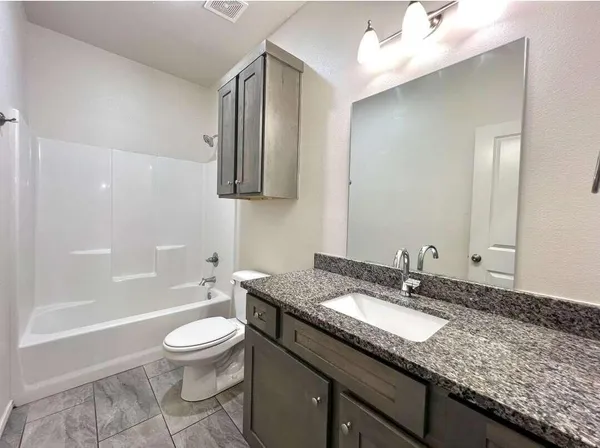 a bathroom with a granite countertop sink a toilet and shower