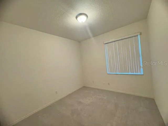 an empty room with a ceiling fan and window