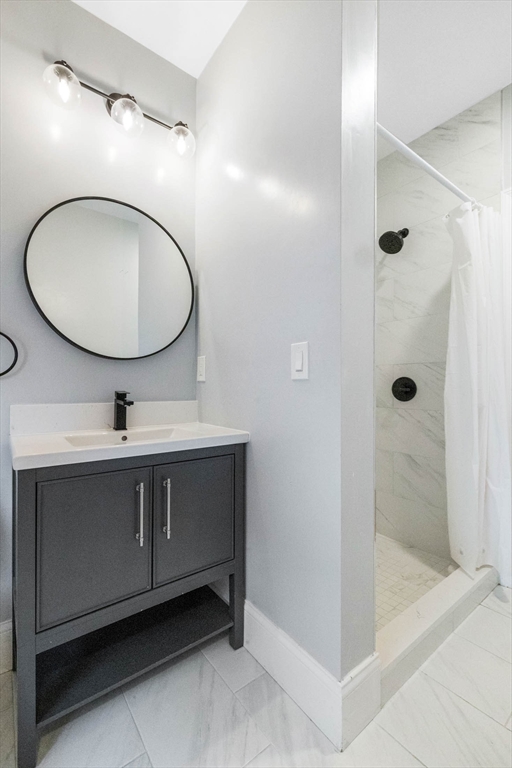 24 Howes Street, Unit 3 Boston, MA 02125 - Photo 7 of 15 a bathroom with a sink a mirror a shower and vanity