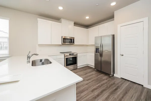 a large white kitchen with kitchen island granite countertop a sink refrigerator and cabinets