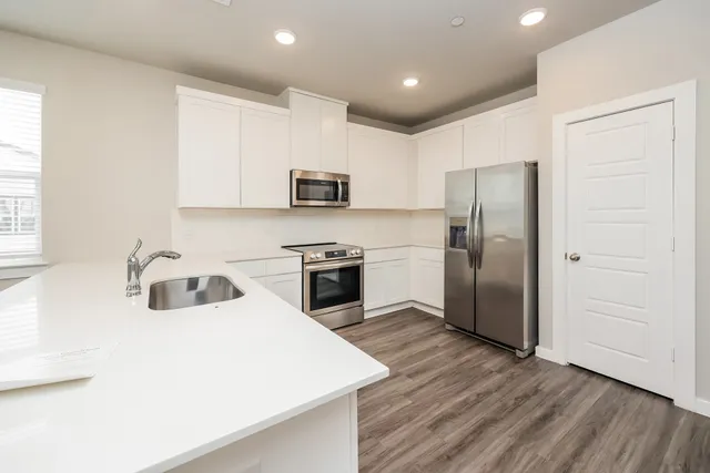 a large white kitchen with kitchen island granite countertop a sink refrigerator and cabinets