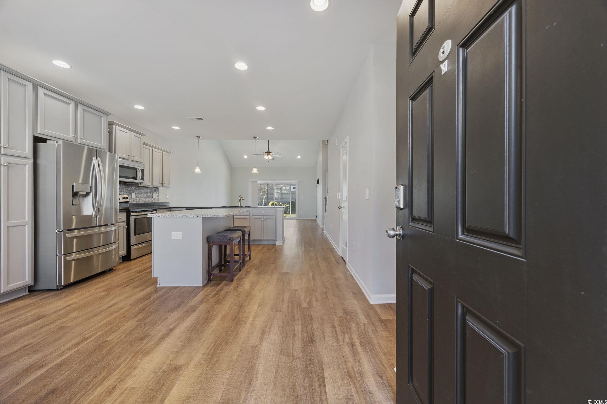 115 Machrie Loop, Unit D Myrtle Beach, SC 29588 - Photo 3 of 40 Kitchen with appliances with stainless steel finishes, gray cabinets, a breakfast bar, decorative light fixtures, and light wood-style floors