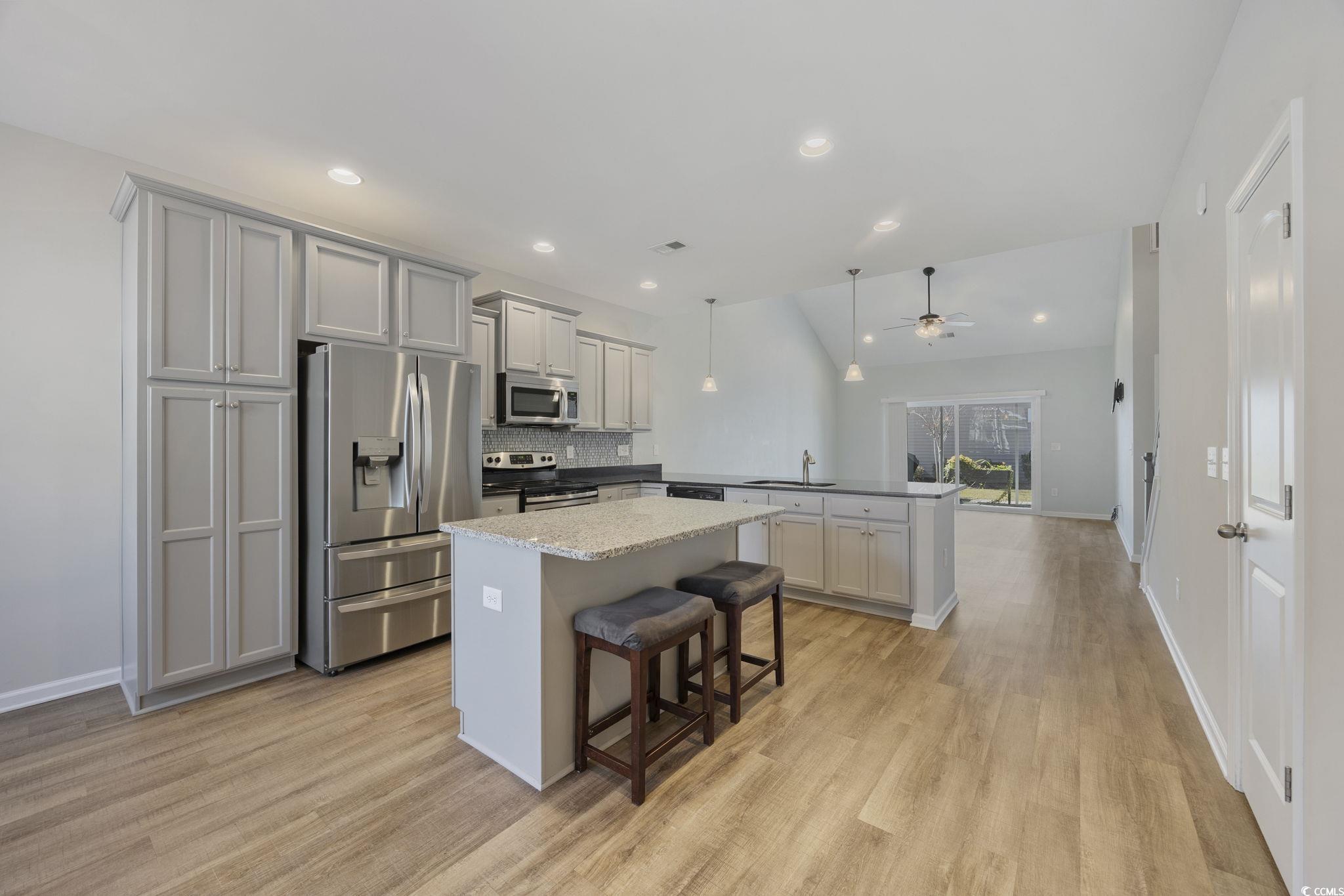 115 Machrie Loop, Unit D Myrtle Beach, SC 29588 - Photo 4 of 40 Kitchen with stainless steel appliances, a breakfast bar, tasteful backsplash, decorative light fixtures, and a kitchen island
