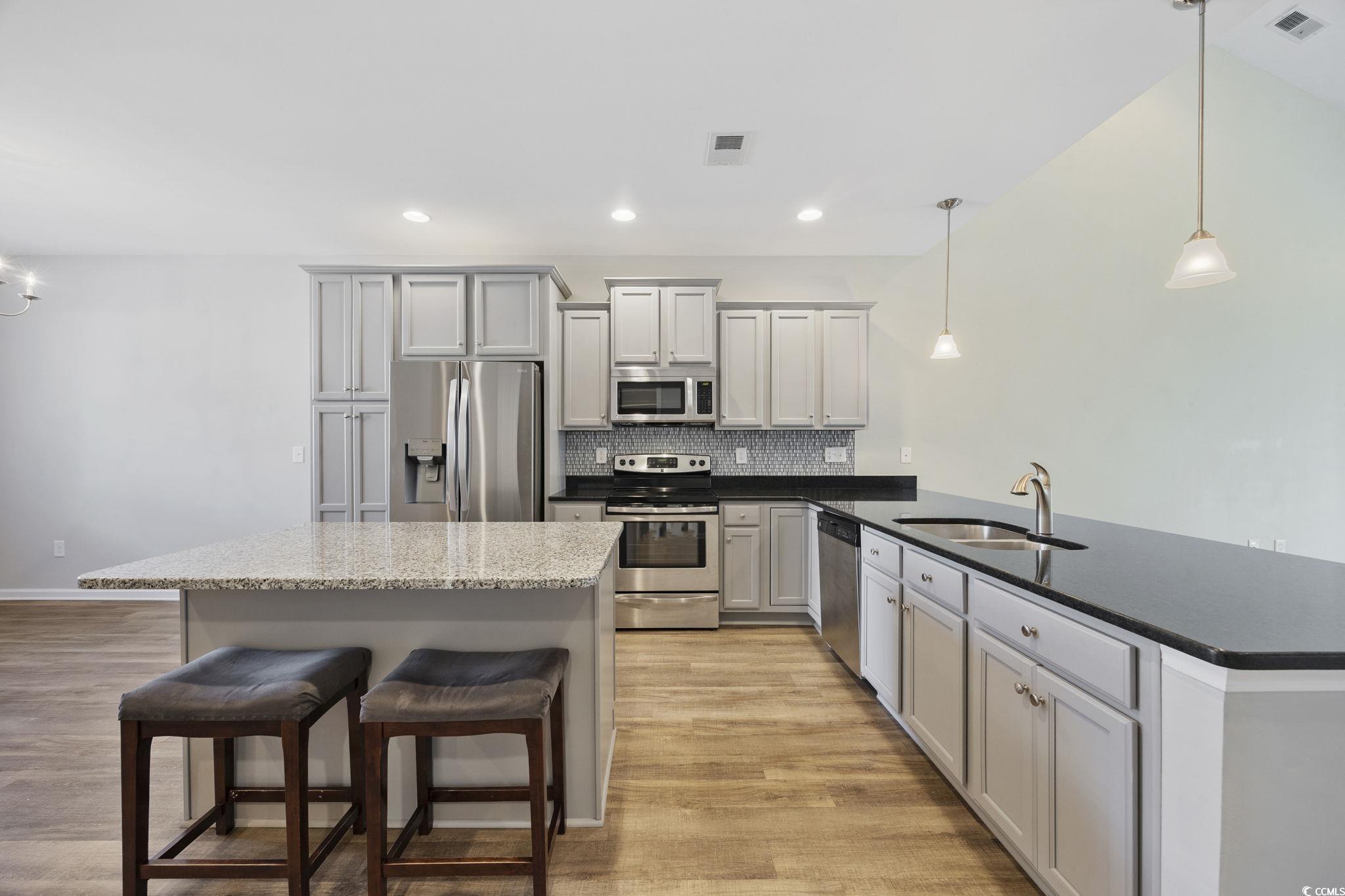 115 Machrie Loop, Unit D Myrtle Beach, SC 29588 - Photo 5 of 40 Kitchen with decorative light fixtures, a breakfast bar, stainless steel appliances, tasteful backsplash, and dark stone countertops