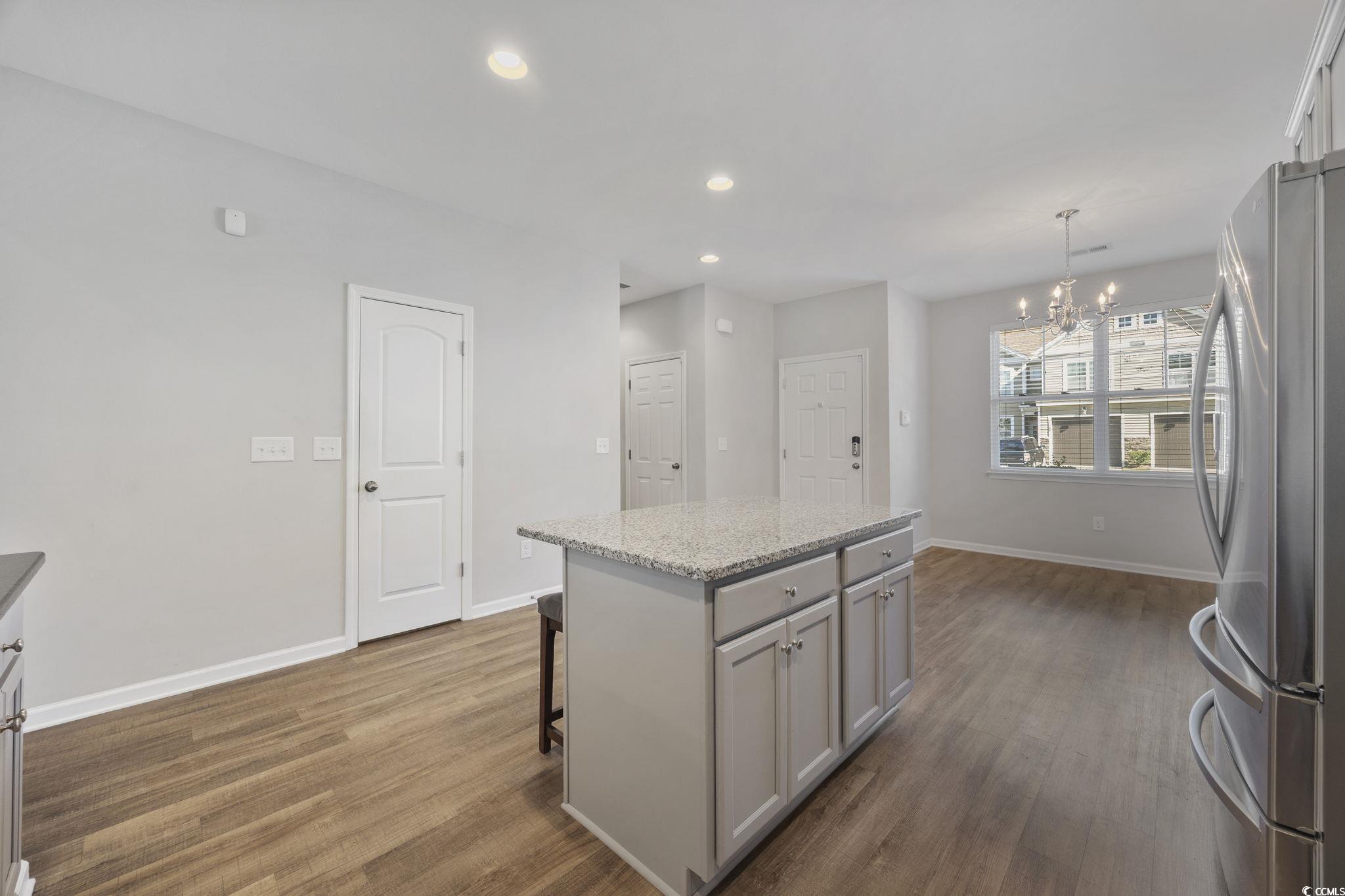 115 Machrie Loop, Unit D Myrtle Beach, SC 29588 - Photo 7 of 40 Kitchen featuring a kitchen island, freestanding refrigerator, recessed lighting, light stone countertops, and hanging light fixtures
