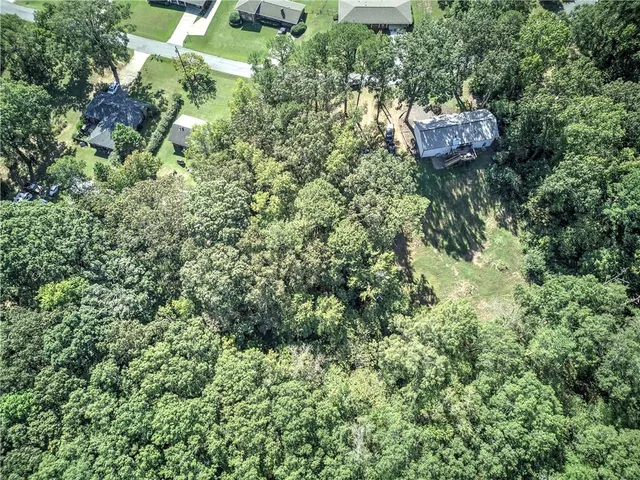 an aerial view of residential house with outdoor space and trees all around