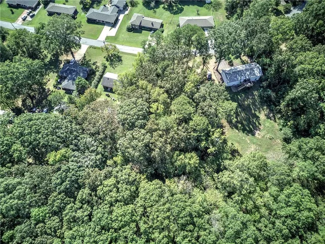 an aerial view of residential house with outdoor space and trees all around