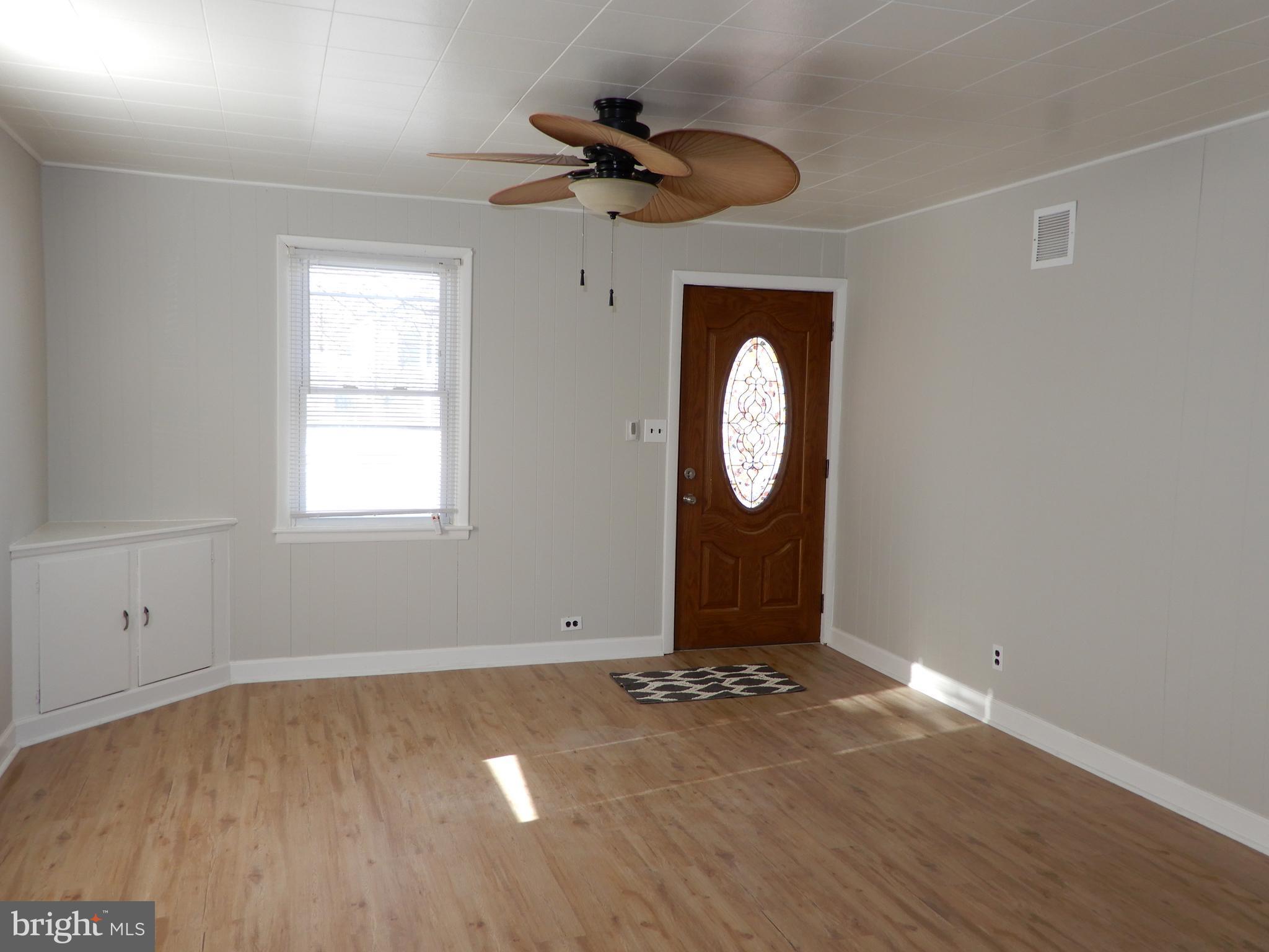 7606 Poplar Road Baltimore, MD 21222 - Photo 5 of 18 an empty room with wooden floor and a window