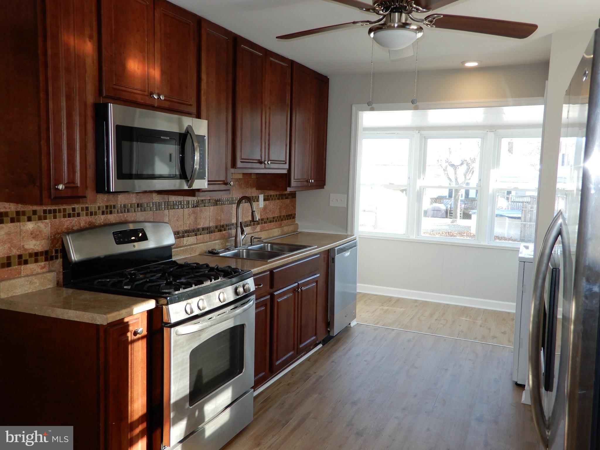 7606 Poplar Road Baltimore, MD 21222 - Photo 7 of 18 a kitchen with stainless steel appliances granite countertop a stove a sink and a microwave