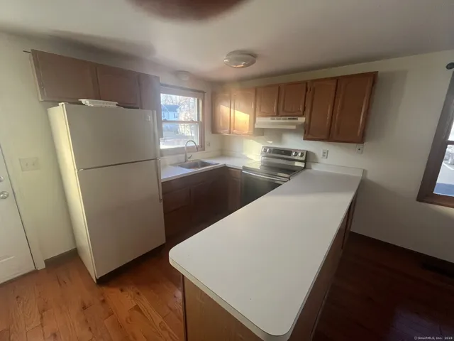 a kitchen with granite countertop a refrigerator a sink a stove a microwave a counter space and cabinets