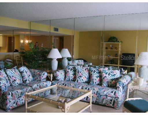 8764 Midnight Pass Road, Unit A403 Sarasota, FL 34242 - Photo 7 of 10 Living Room - Mirrored wall in living and dining with tropical style furnishings