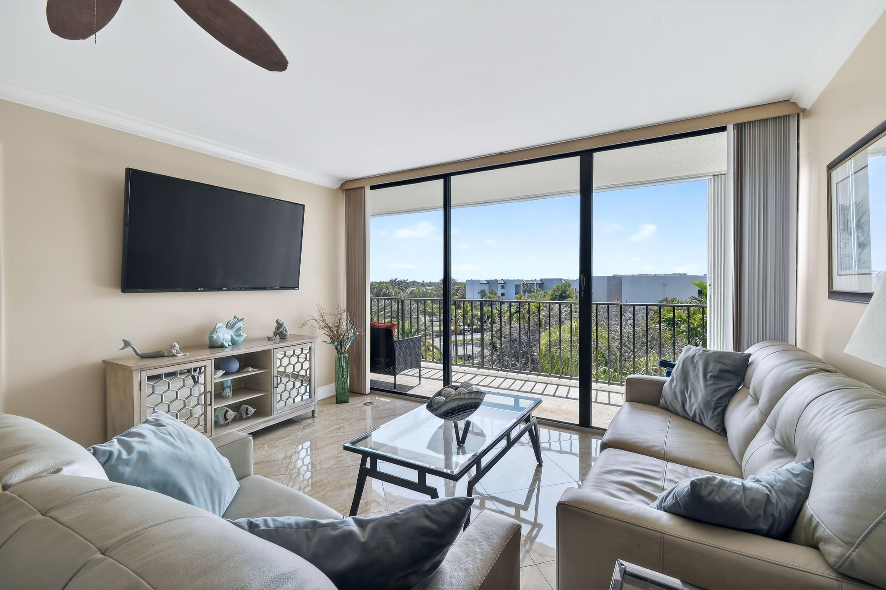 1300 Florida A1A, Unit 320 Jupiter, FL 33477 - Photo 8 of 92 a living room with furniture a flat screen tv and a floor to ceiling window