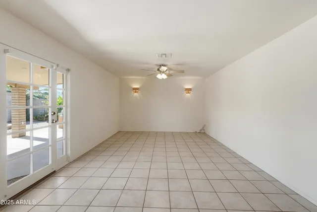 an empty room with chandelier fan and windows