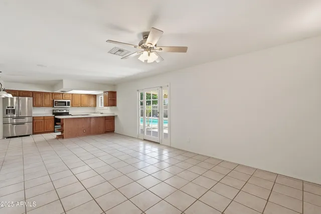 a view of a livingroom with furniture cabinet a ceiling fan and windows