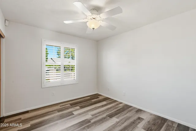 an empty room with a window and ceiling fan