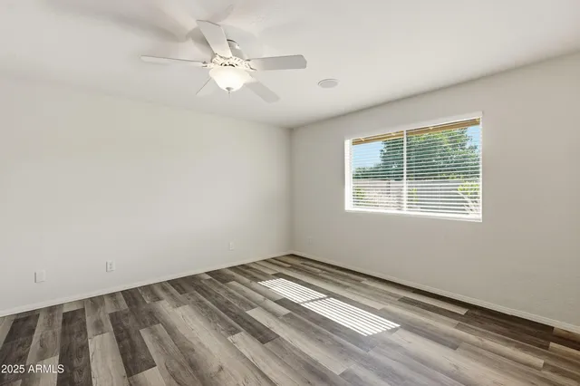 an empty room with wooden floor and ceiling fan