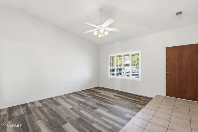 a view of an empty room with window and chandelier fan