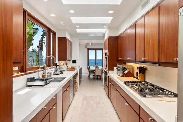 a large white kitchen with stainless steel appliances granite countertop a stove a sink dishwasher and cabinets with wooden floor