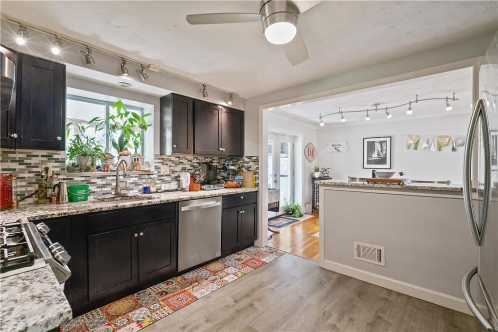 117 Gill Hall Road Clairton, PA 15025 - Photo 12 of 43 Updated kitchen features dark wood cabinetry, granite countertops, stainless steel appliances, tile backsplash, and a gas range. Bright and functional layout opens to dining area.