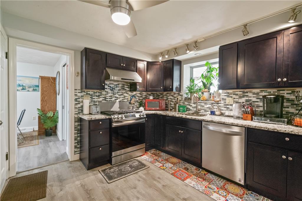 117 Gill Hall Road Clairton, PA 15025 - Photo 10 of 43 Updated kitchen features dark wood cabinetry, granite countertops, stainless steel appliances, tile backsplash, and a gas range. Bright and functional layout opens to dining area.