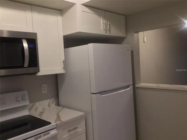 a kitchen with white cabinets and sink