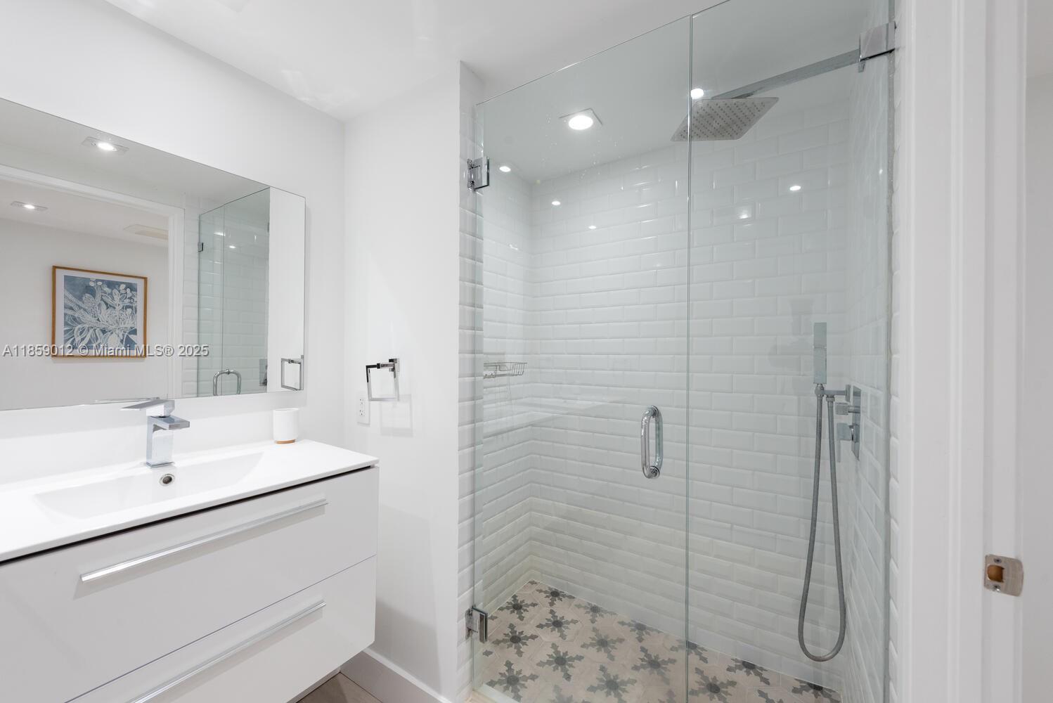 181 Crandon Boulevard, Unit 306 Key Biscayne, FL 33149 - Photo 17 of 25 a bathroom with a shower sink and mirror
