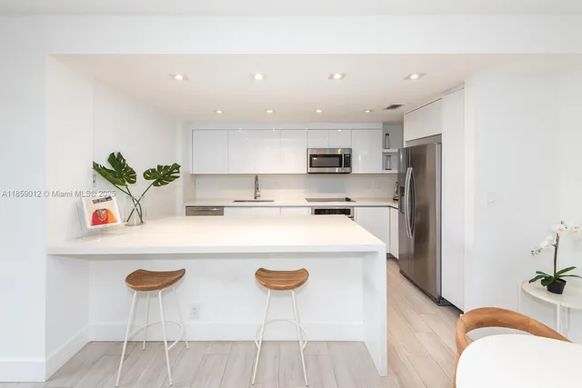 a kitchen with stainless steel appliances a white refrigerator a stove a sink a dining table and chairs