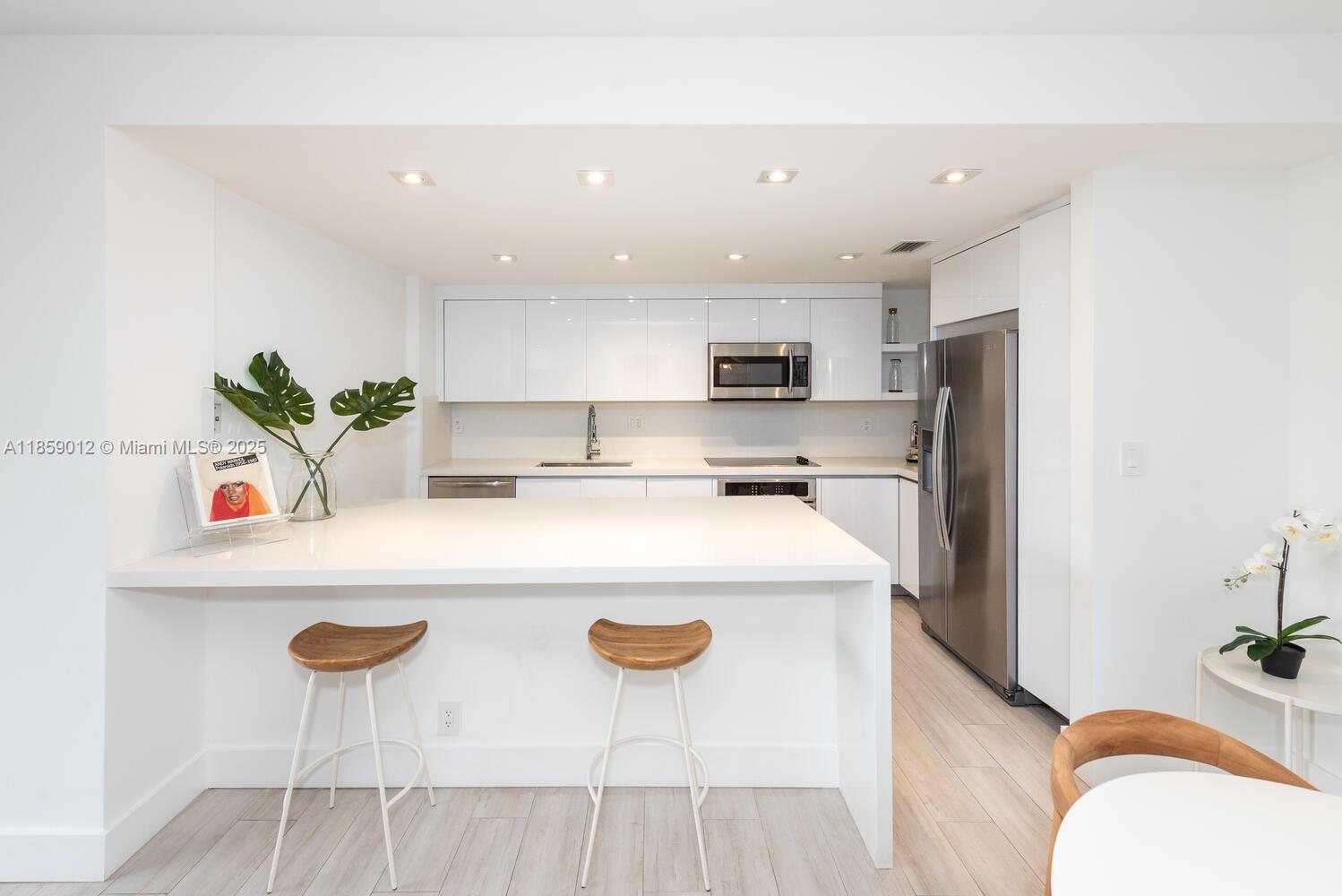 181 Crandon Boulevard, Unit 306 Key Biscayne, FL 33149 - Photo 6 of 25 a kitchen with stainless steel appliances a white refrigerator a stove a sink a dining table and chairs